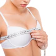 Close up of young woman measuring her bust size with tape measure