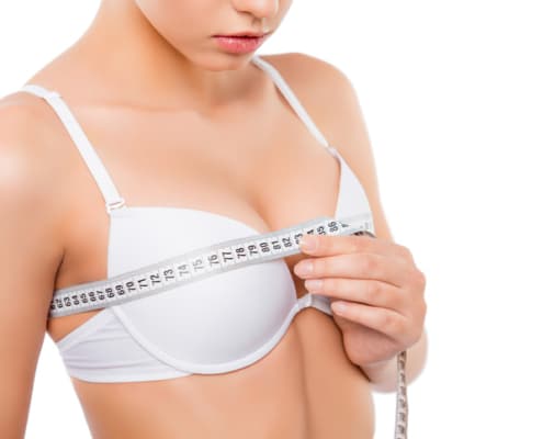 Close up of young woman measuring her bust size with tape measure