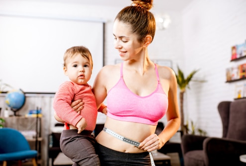 Young mother in sportswear measuring her waist worried about her weight after the child birth