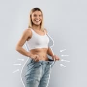 Woman wearing jeans that are too big, showing off her slim body from liposuction
